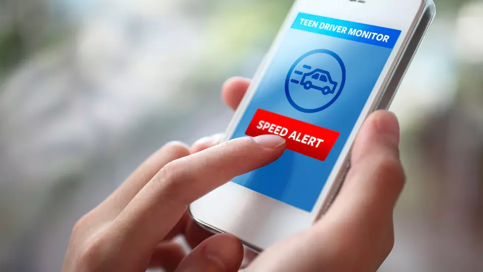 Parent checking teen driver safety app on smartphone.