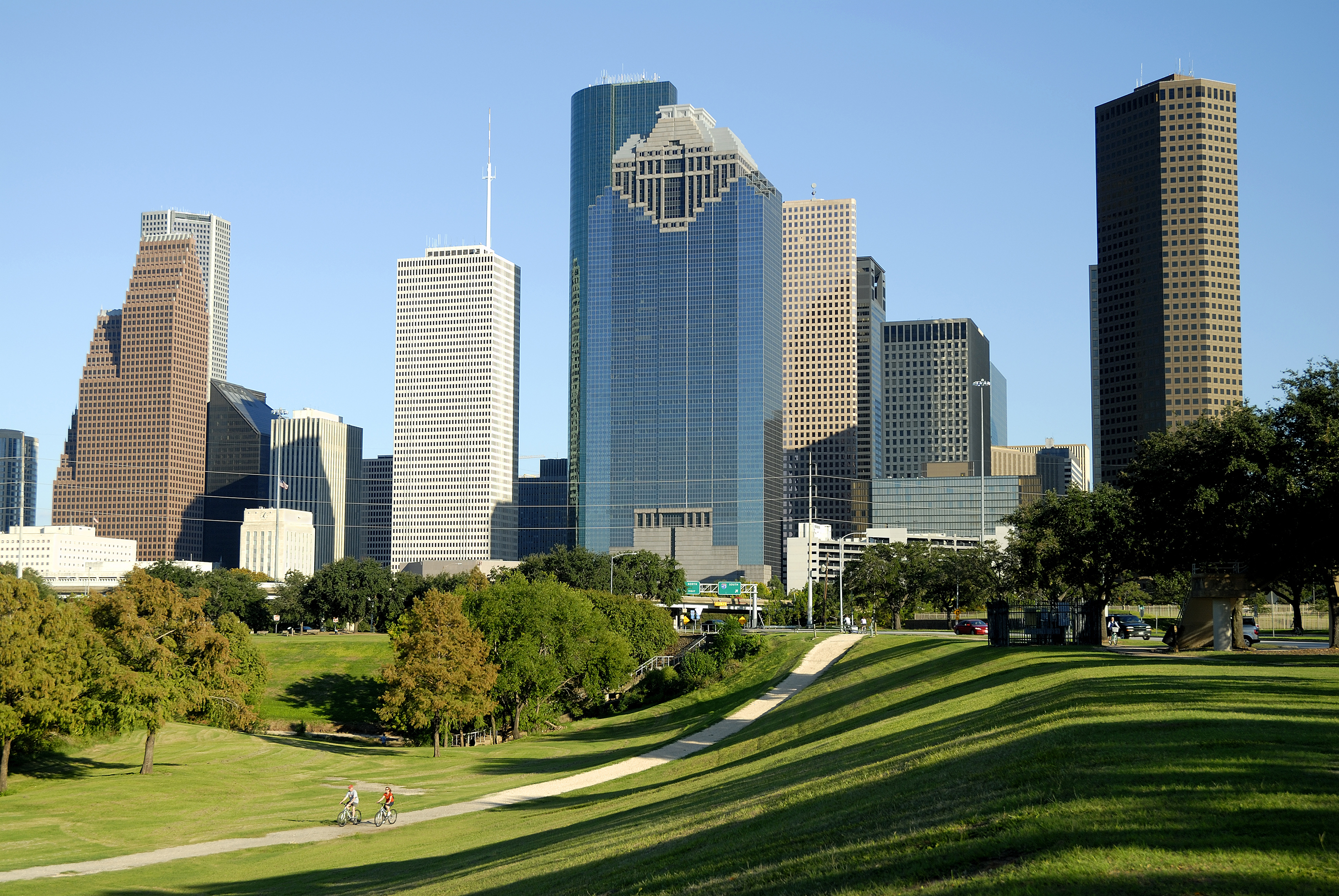 A park with luscious grass next to the city with skyscrapers.