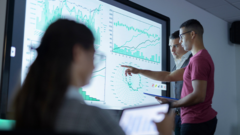 two men looking at screen with graphs.