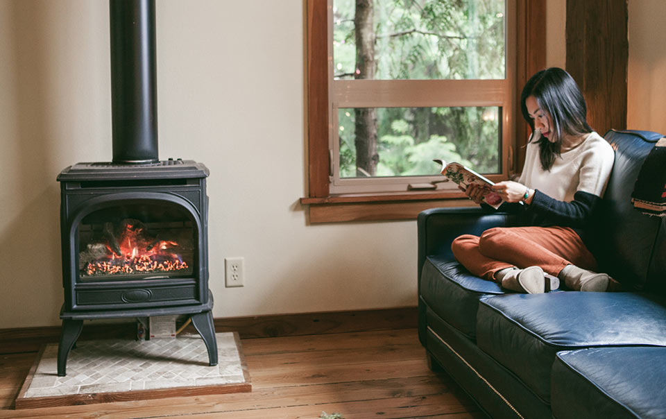 Woman sitting on couch next to pellet stove