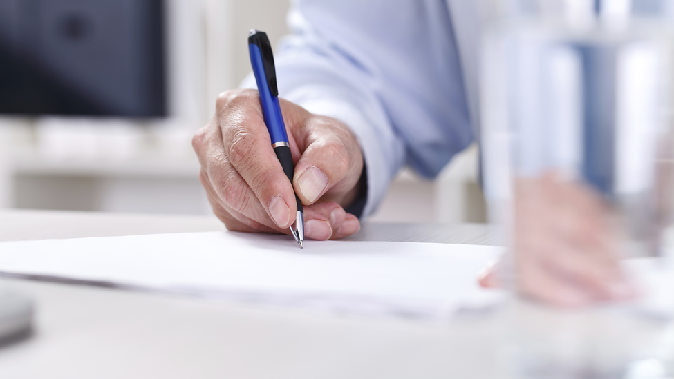 Male hand writing on a paper, signing a contract