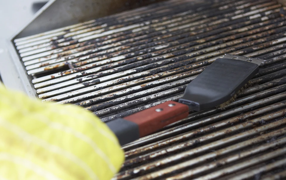 Person cleaning a gas grill.