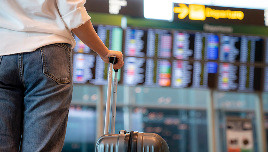 Insured person traveling holding suitcase in an airport.