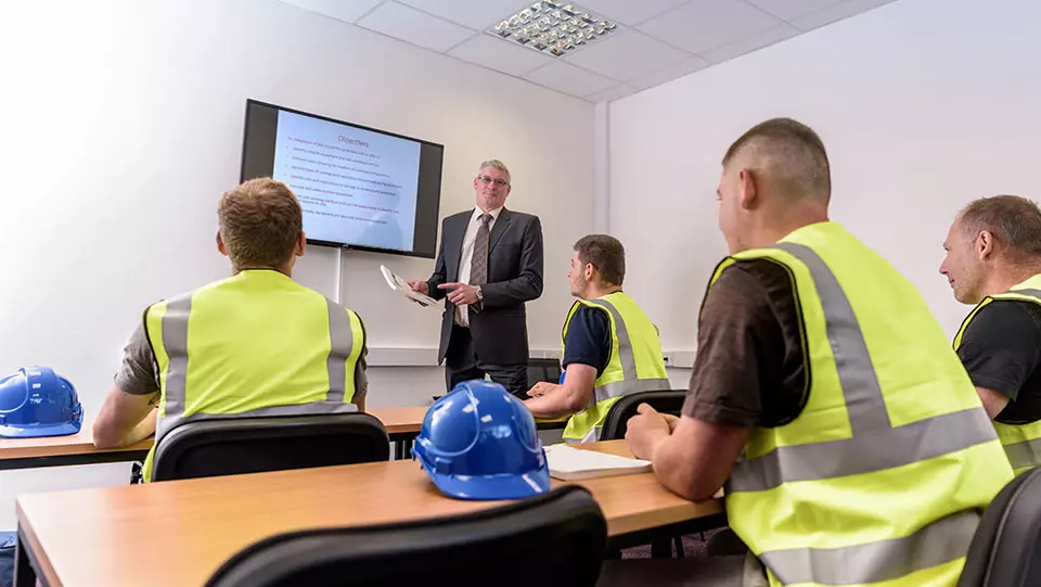 Person onboarding construction workers in a classroom.