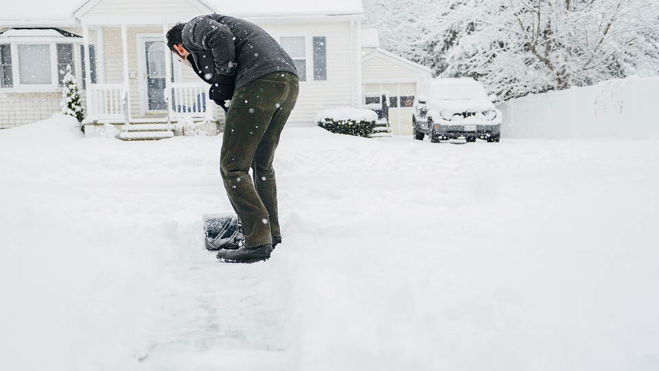 Person shoveling snow outside house.