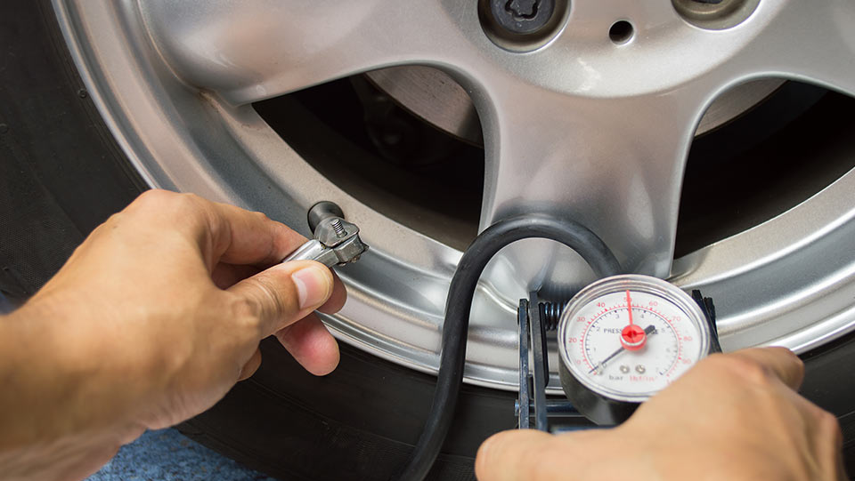 Person testing tire pressure as part of car maintenance checklist.
