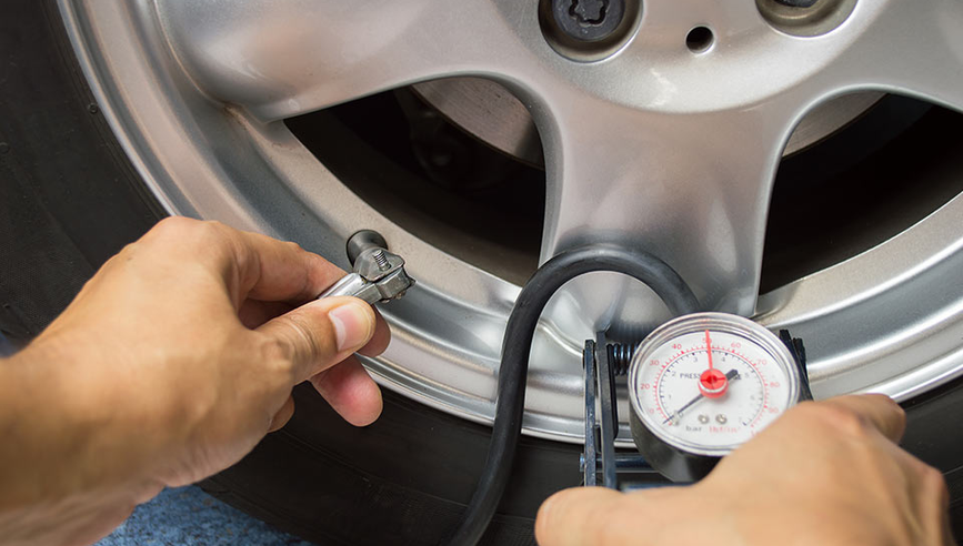 Person testing tire pressure as part of car maintenance checklist.