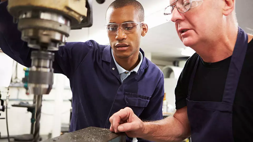 Person training new manufacturing worker on jobsite.