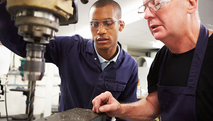 Person training new manufacturing worker on jobsite.