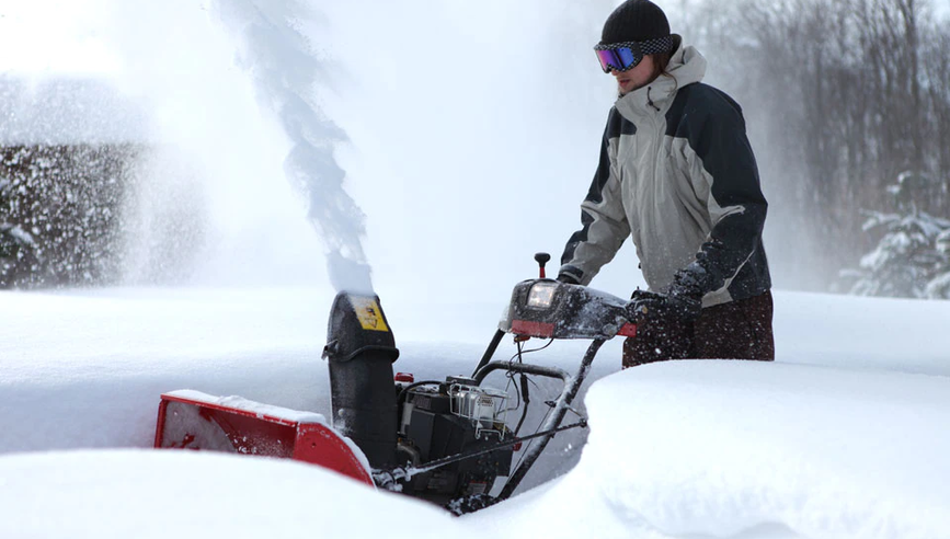 Person using snow blower to remove snow from driveway.