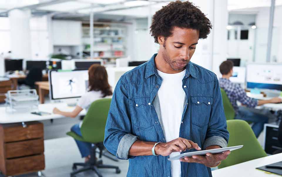 Person standing in office looking at a tablet