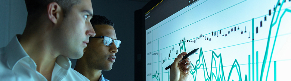 Businessmen studying graphs on an interactive screen in business meeting.