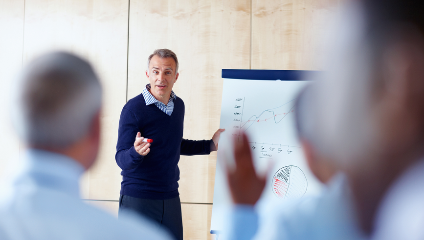 Senior Business man giving presentation to group of colleagues.