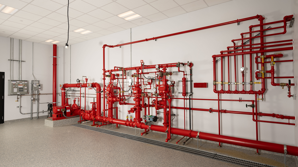 A set of pipes and valves connected to a large red pipe. 