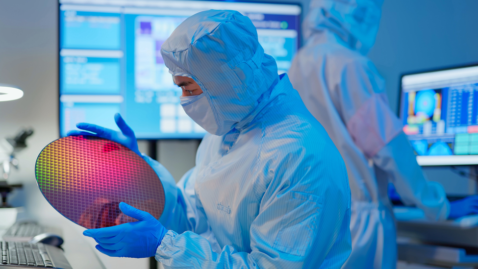 Professional engineer in a safety suit observing a semiconductor.