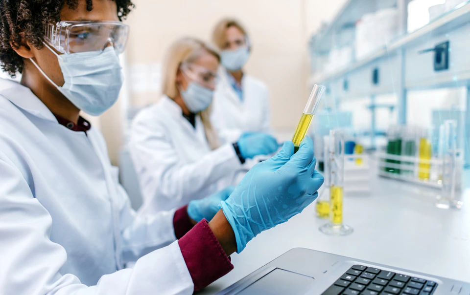 Professionals in lab coats working with text tubes in a lab.