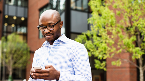 Customer standing outside an office building looking at his phone.