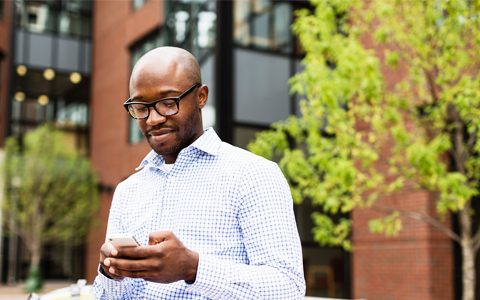 Customer standing outside an office building looking at his phone.