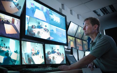 Man viewing computer display of security camera footage.