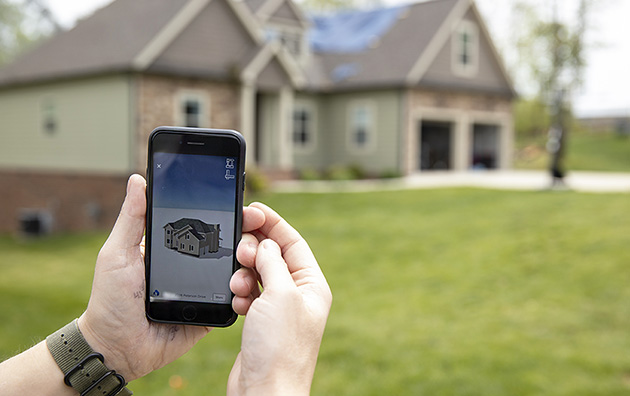 Property inspector measuring a house with virtual measurement phone app.