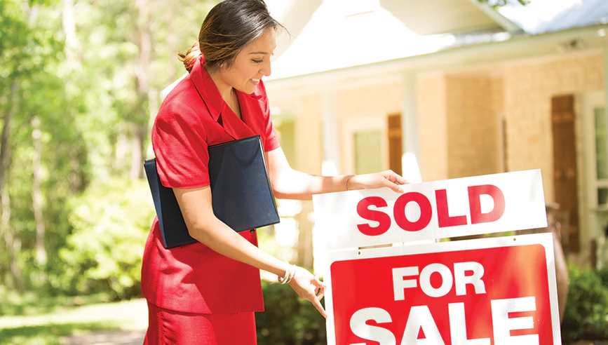 Real estate agent changing for sale sign to sold.