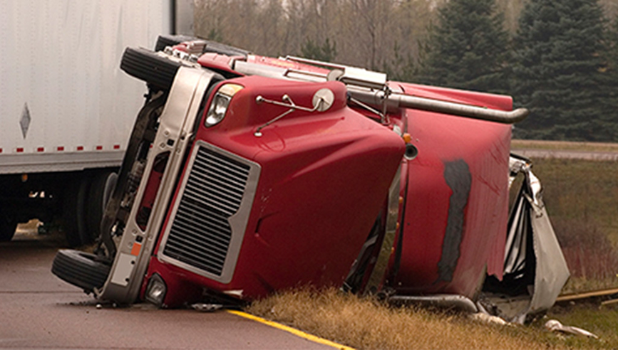 Red semi truck overturned in ditch off road. 