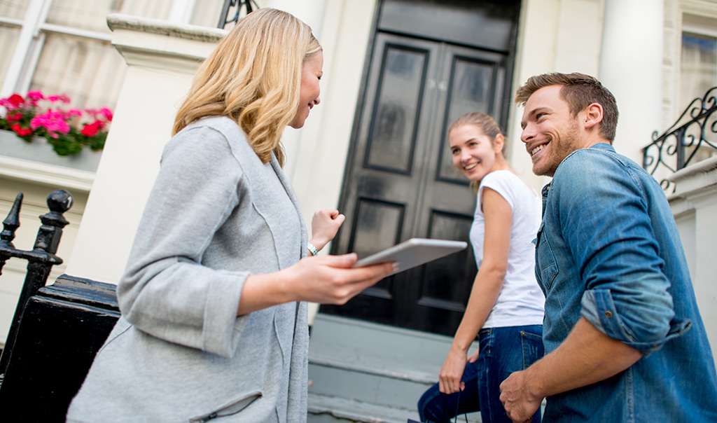 Landlord showing rental property to young couple.