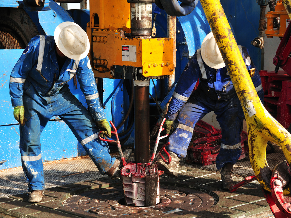 Energy workers help repair oilfield machinery their company has supplied.