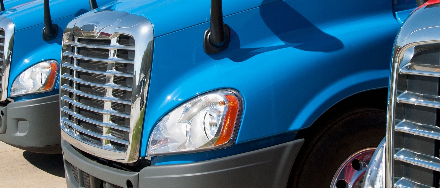 Row of blue trucks in a lot.