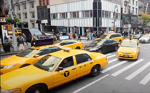 Yellow taxi cab on a busy city street.