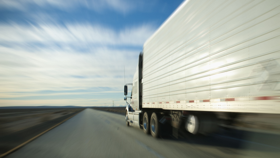 18-wheeler truck moving along flat, empty highway 