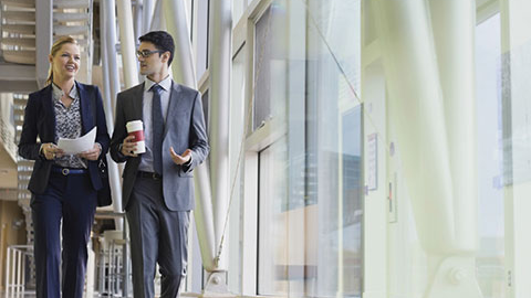 Two people discussing employment practice liability while walking down a hallway.