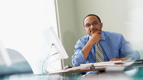 Business person with thinking expression sitting at desk.