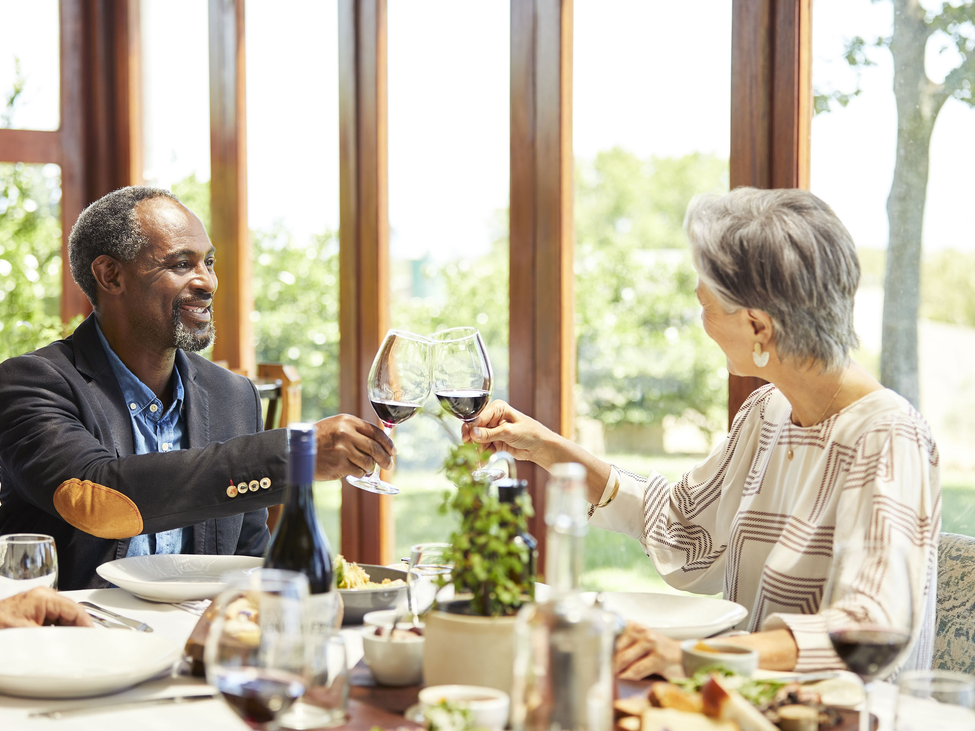 A couple raises wine glasses for a toast at a fine restaurant. 