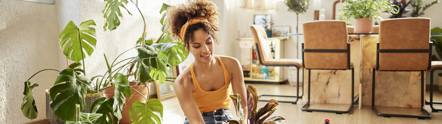 A woman is sitting on the floor of her condo repotting plants.