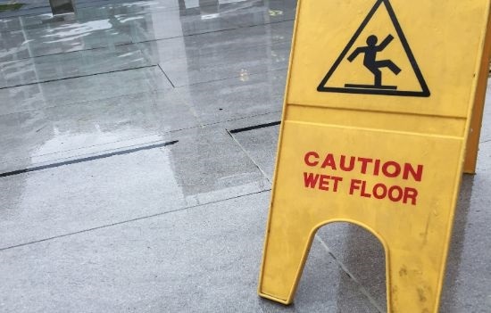 Caution wet floor sign on a wet concrete walkway.