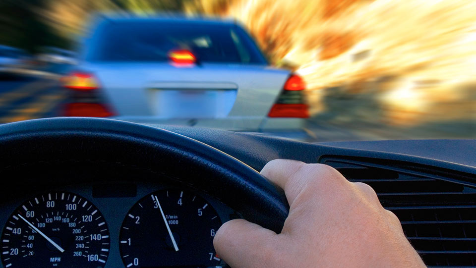 Person driving behind a car and sharing the road with another car.