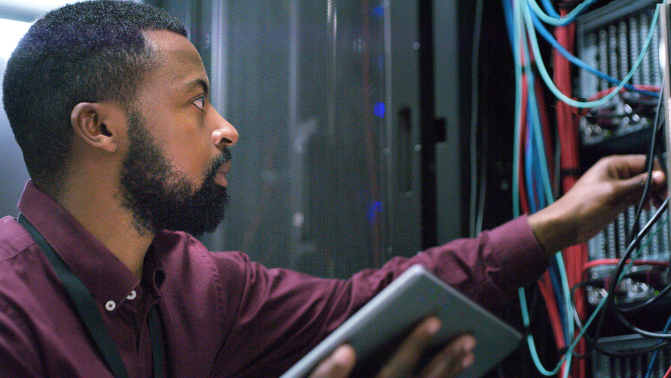 Technician checking a server room for cloud computing or cyber security. IT engineer working on database for maintenance or networking in a data center.