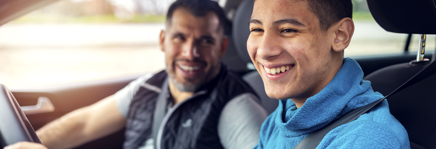 Father teaches teen son how to drive.