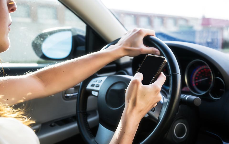 Teenager texting behind the wheel of a car.