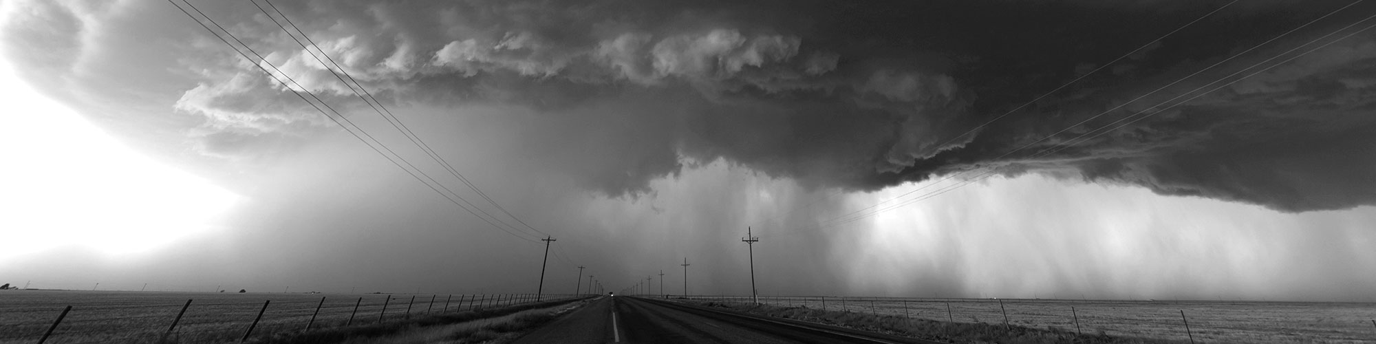 Prairie road with heavy rain in the distance.