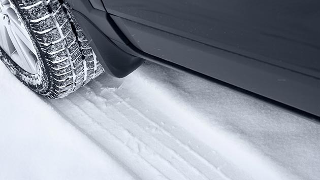 Car tire driving over snow.