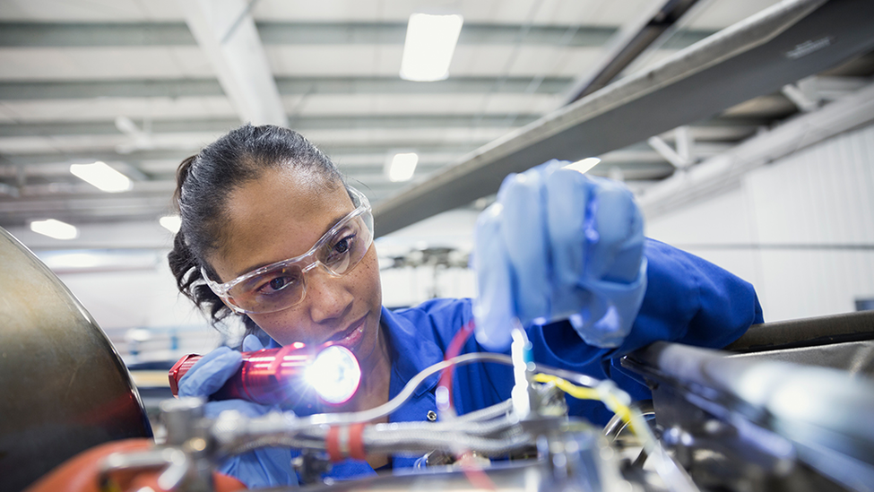 Woman working on machine with safety glasses on.