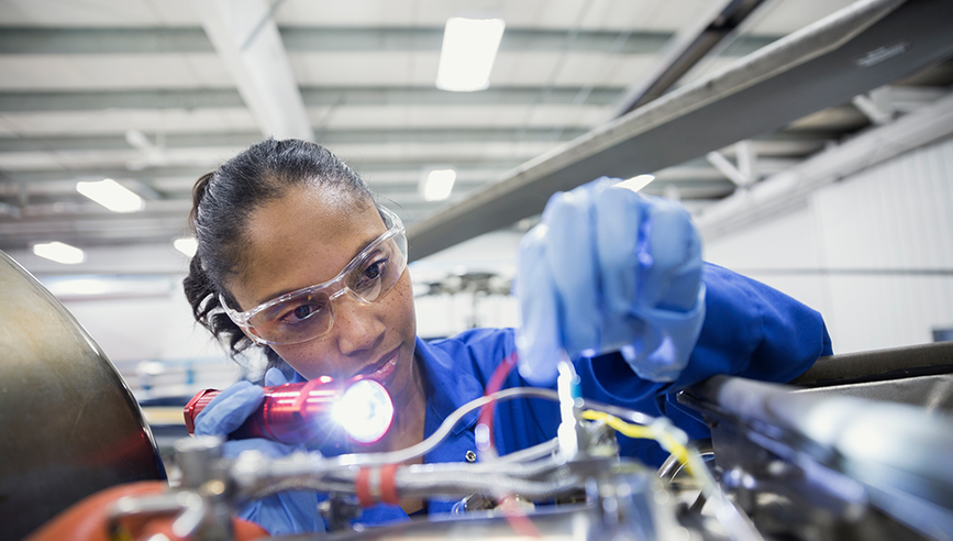 Woman working on machine with safety glasses on.