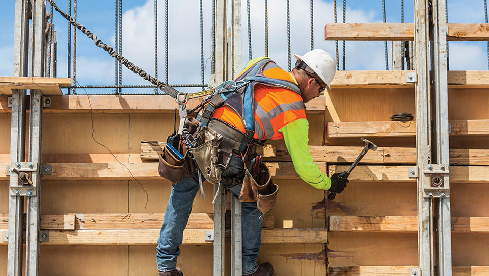 Construction worker safely tethered while working on a building.