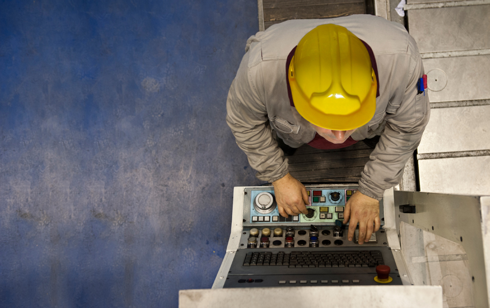 Man in yellow hard hat working on laptop.