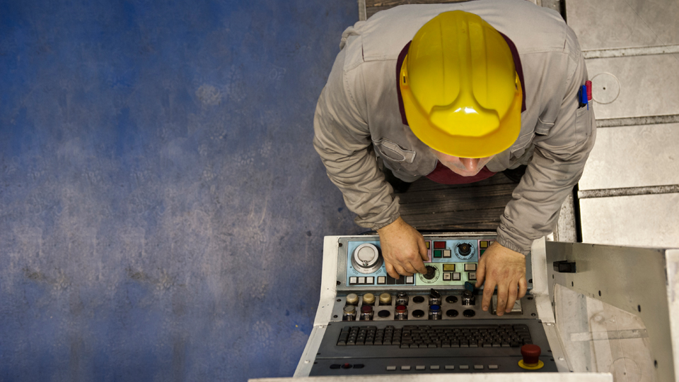 Man in yellow hard hat working on laptop.