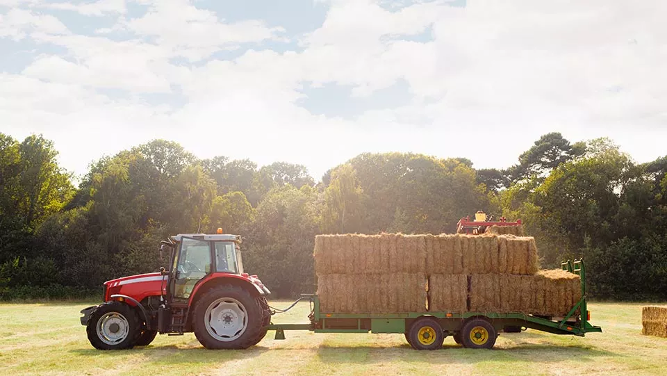 Tractor pulling hay pile on a farm.