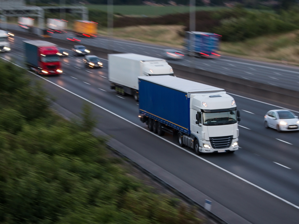 Trucks on the motorway alongside smaller cars.