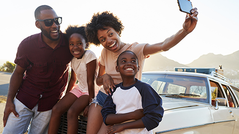 Family taking a selfie in front of a car.